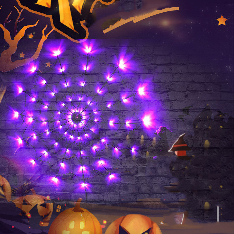 Purple LED spider web light glowing on a brick wall with Halloween pumpkins